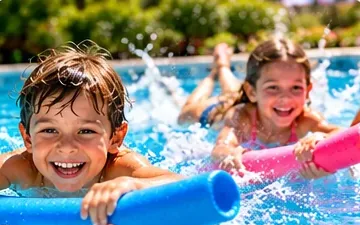 Deux enfants avancent à la surface de l’eau en tenant chacun une frite de piscine