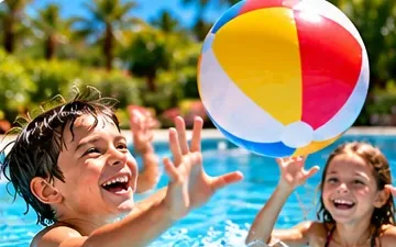 Un garçon et une fillette frappent un ballon de plage au-dessus de l’eau de la piscine